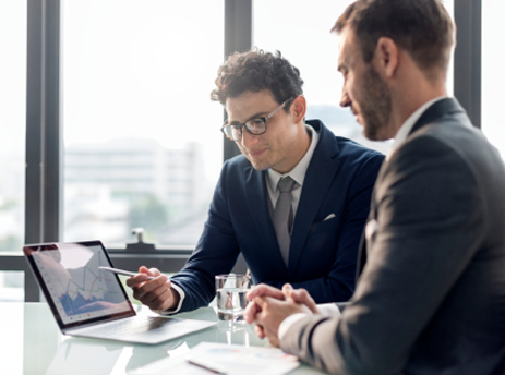 Two men looking at a laptop displaying data analytics